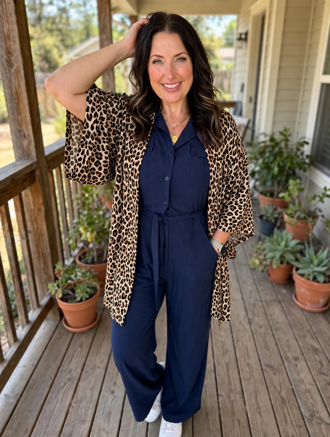 Jessica Peavey smiling on a porch in a navy jumpsuit and leopard cardigan